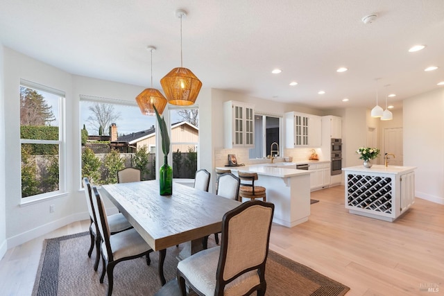 dining space with light wood-style flooring, recessed lighting, and baseboards