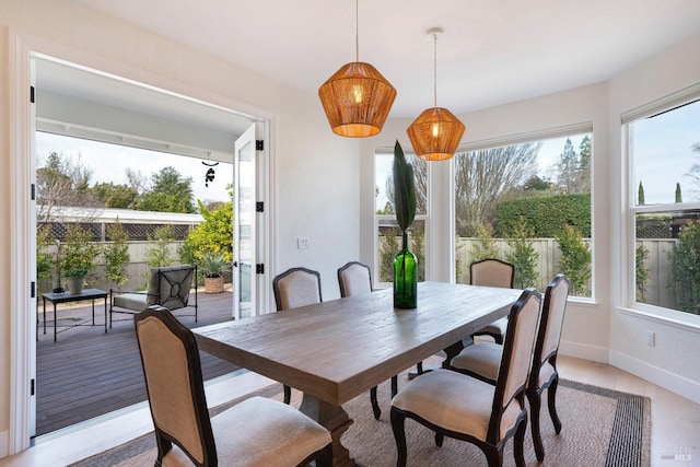 dining area with baseboards, plenty of natural light, and light wood-style flooring