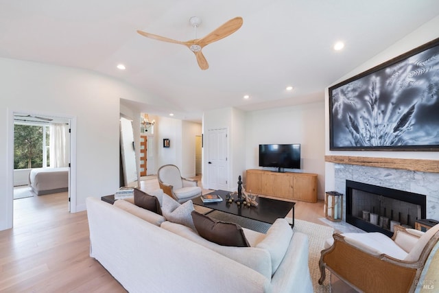 living area featuring lofted ceiling, recessed lighting, light wood-style flooring, a fireplace, and a ceiling fan