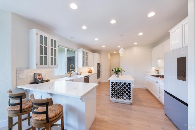 kitchen with a sink, light wood-style floors, tasteful backsplash, and stainless steel appliances