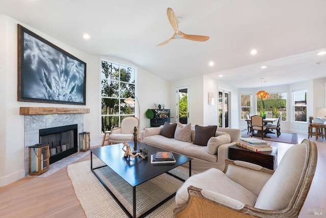 living area with recessed lighting, a fireplace with flush hearth, light wood-style floors, and vaulted ceiling