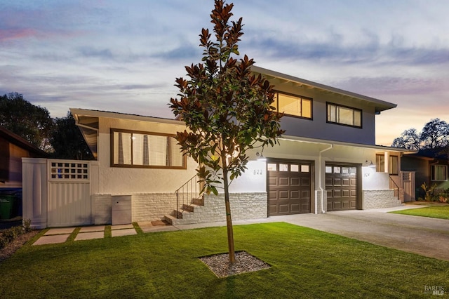 view of front facade with a yard, driveway, a garage, and stucco siding