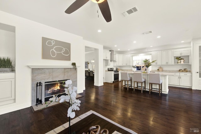 living area with visible vents, dark wood-style flooring, and a tile fireplace