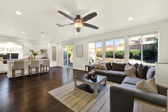 living area with baseboards, visible vents, dark wood-type flooring, and recessed lighting