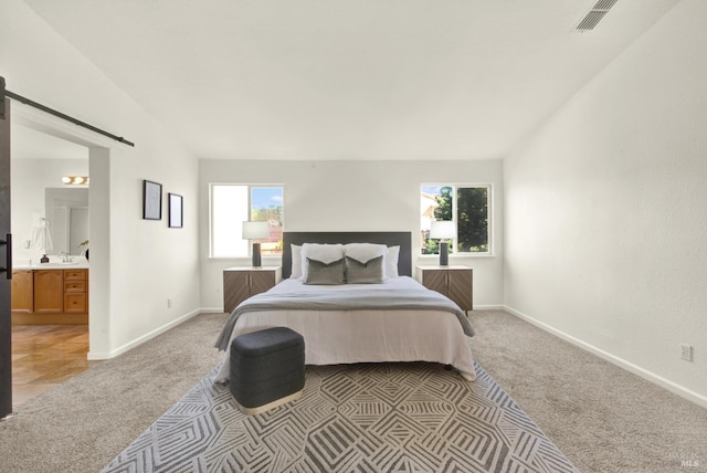 bedroom with light carpet, visible vents, multiple windows, and a barn door