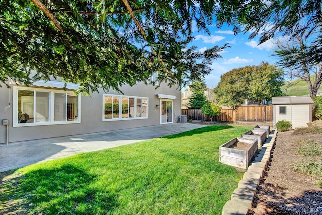 view of yard with a fenced backyard, an outdoor structure, a vegetable garden, a shed, and a patio area