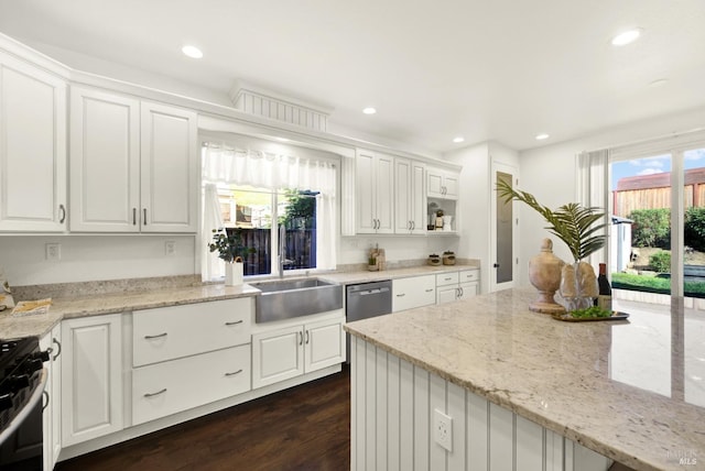 kitchen with light stone counters, dark wood-style floors, range with gas cooktop, white cabinetry, and a sink