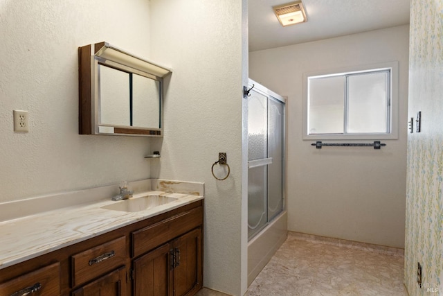 bathroom featuring visible vents, combined bath / shower with glass door, and vanity