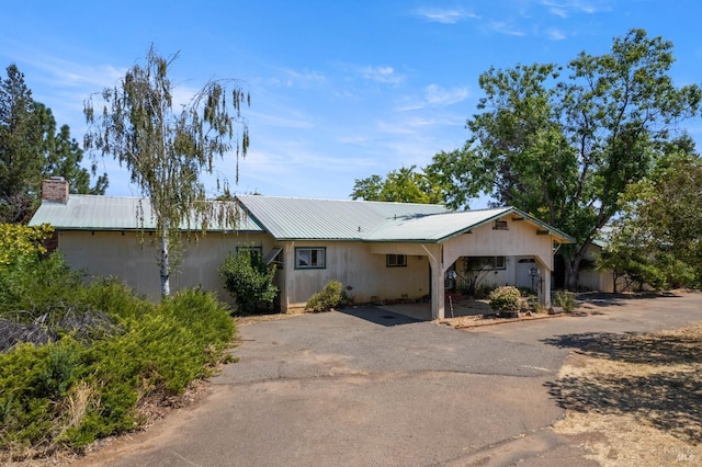 ranch-style house with metal roof, aphalt driveway, and a chimney