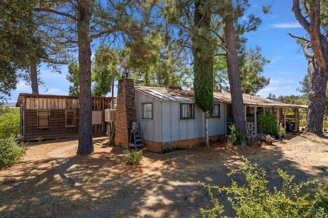 view of front of house featuring metal roof, a chimney, and board and batten siding