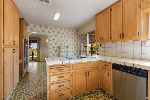 kitchen with wallpapered walls, tile counters, stainless steel appliances, and arched walkways