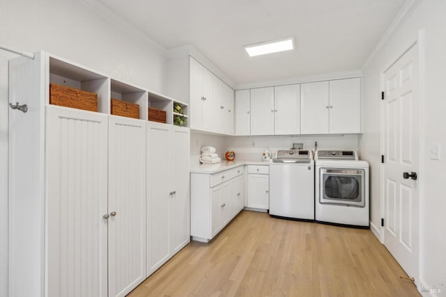 laundry room featuring light wood-type flooring, cabinet space, crown molding, and separate washer and dryer