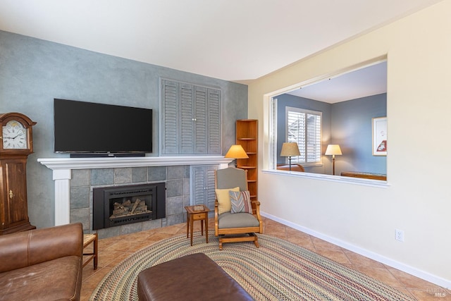 living area with a tiled fireplace, tile patterned floors, and baseboards