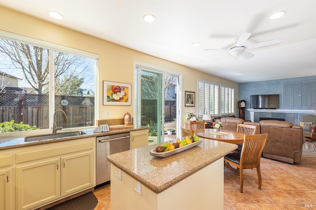 kitchen featuring light stone counters, a center island, recessed lighting, stainless steel dishwasher, and a sink