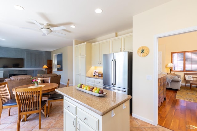 kitchen with light tile patterned floors, high quality fridge, recessed lighting, open floor plan, and a center island