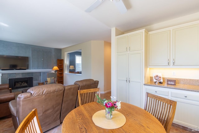 dining room featuring a ceiling fan and a tiled fireplace