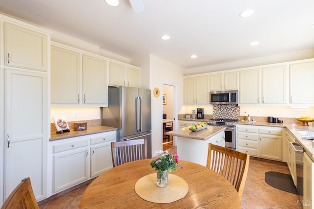 kitchen with light tile patterned floors, high end appliances, a center island, and recessed lighting