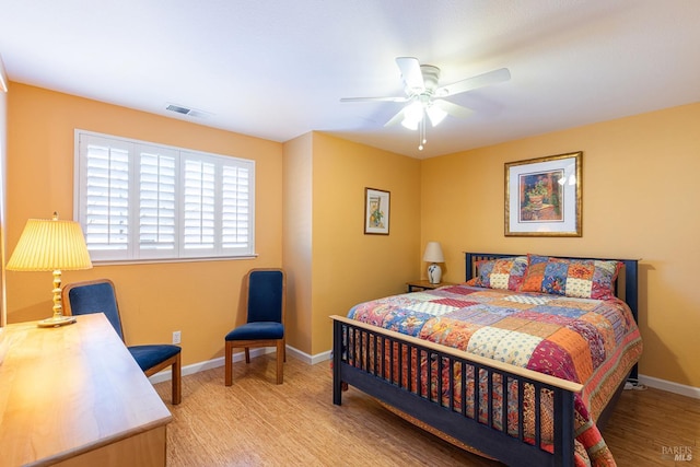 bedroom with a ceiling fan, wood finished floors, visible vents, and baseboards