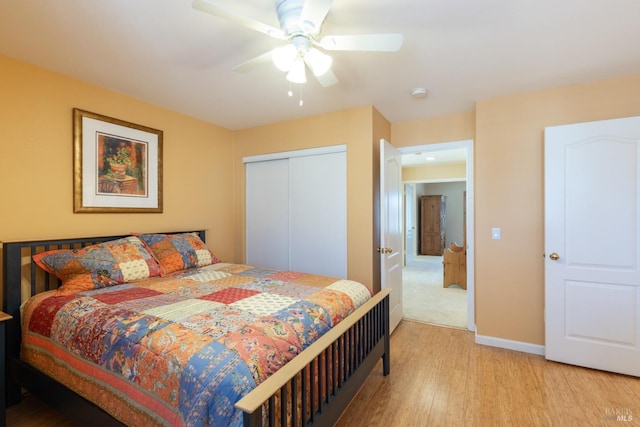 bedroom featuring a closet, ceiling fan, light wood-style flooring, and baseboards