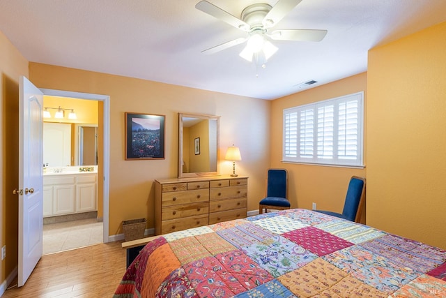 bedroom featuring ensuite bathroom, ceiling fan, light wood-style flooring, visible vents, and baseboards