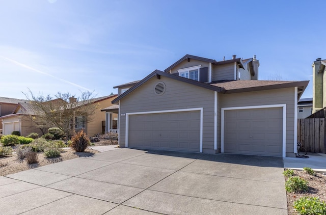 view of front facade with driveway, an attached garage, and fence