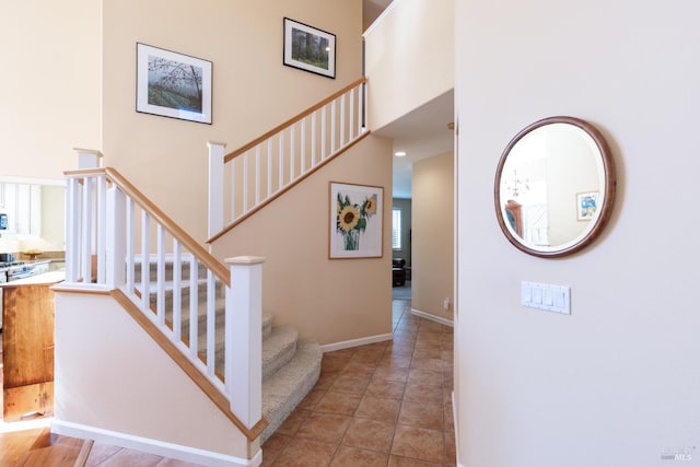 staircase with a high ceiling, tile patterned flooring, and baseboards