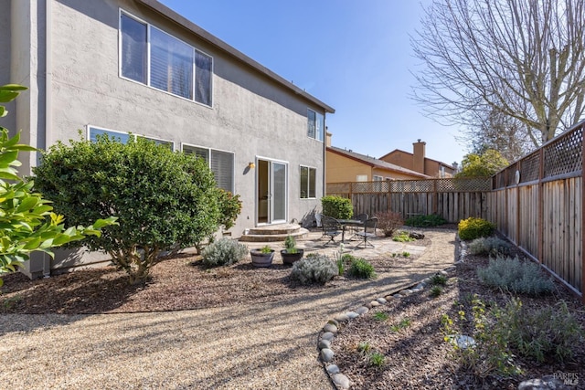 rear view of house with a fenced backyard, a patio, and stucco siding