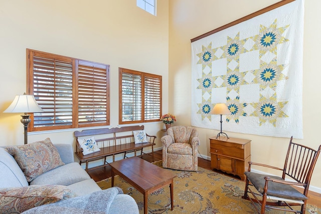 living room featuring a high ceiling, wood finished floors, and baseboards