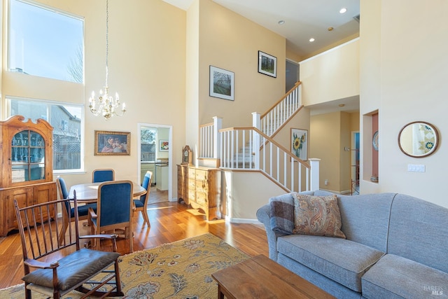 living room with baseboards, a towering ceiling, wood finished floors, stairs, and a chandelier