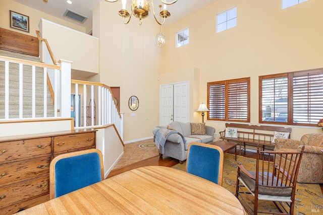 living room with baseboards, visible vents, a high ceiling, stairs, and a notable chandelier