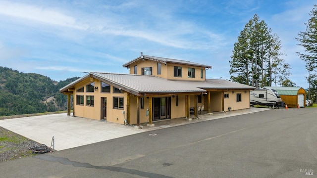 view of front of house featuring a patio area, metal roof, an outdoor structure, and a shed