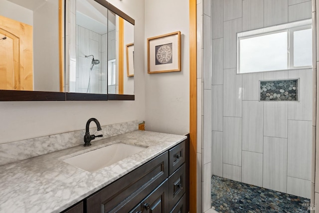 bathroom featuring a tile shower and vanity