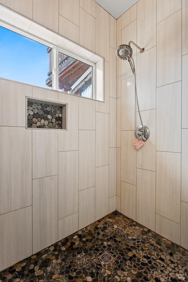 bathroom featuring stone finish floor and tiled shower