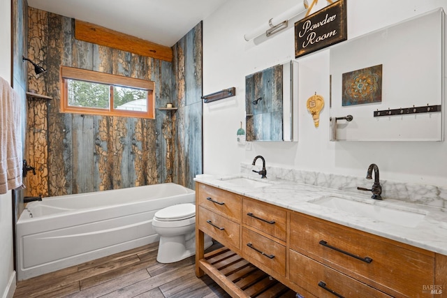 bathroom with double vanity, wood finished floors, a sink, and toilet