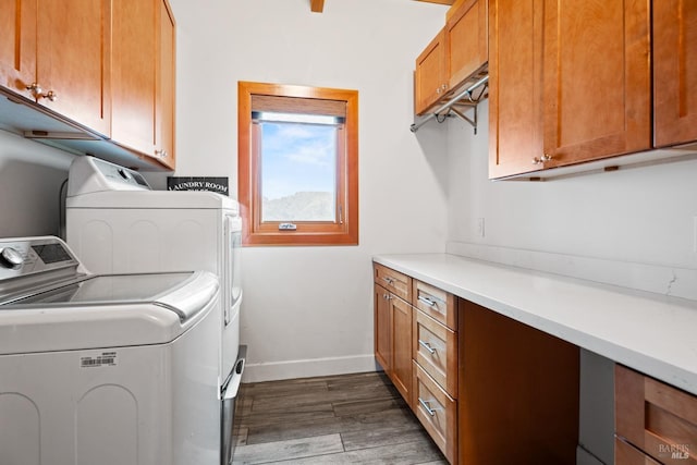 clothes washing area featuring dark wood-type flooring, washer and dryer, cabinet space, and baseboards