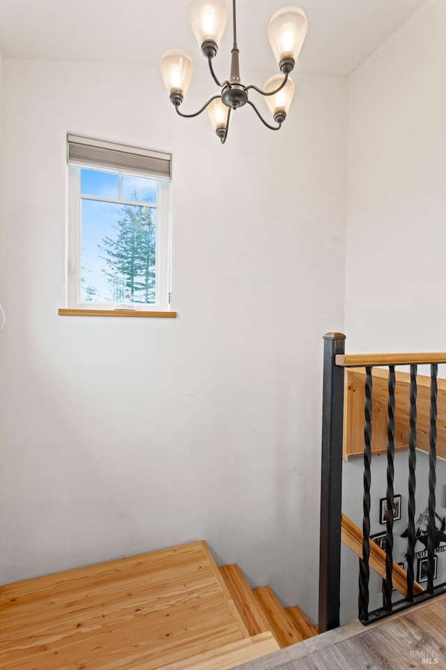 stairway featuring a chandelier and wood finished floors