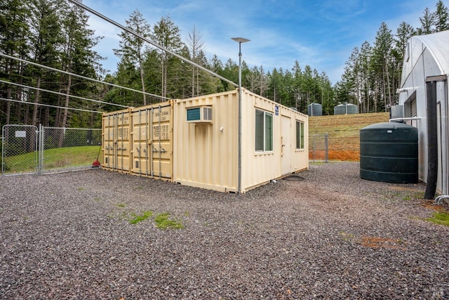 view of outbuilding featuring fence and a wall mounted AC