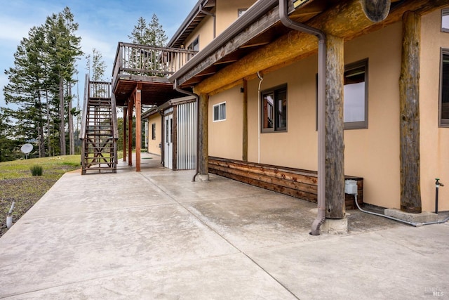 view of home's exterior with stucco siding, a patio area, and stairs