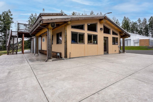 exterior space with a deck, stairway, and stucco siding