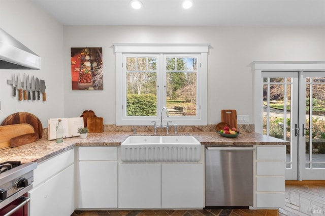 kitchen featuring light stone counters, appliances with stainless steel finishes, extractor fan, white cabinetry, and a sink