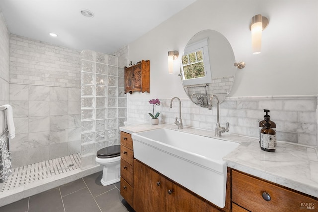 bathroom featuring tile walls, toilet, vanity, tile patterned flooring, and walk in shower