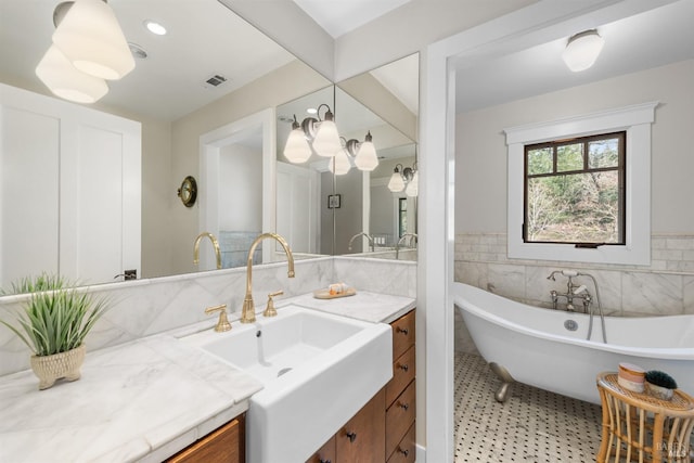 bathroom featuring tile walls, visible vents, a freestanding bath, and vanity