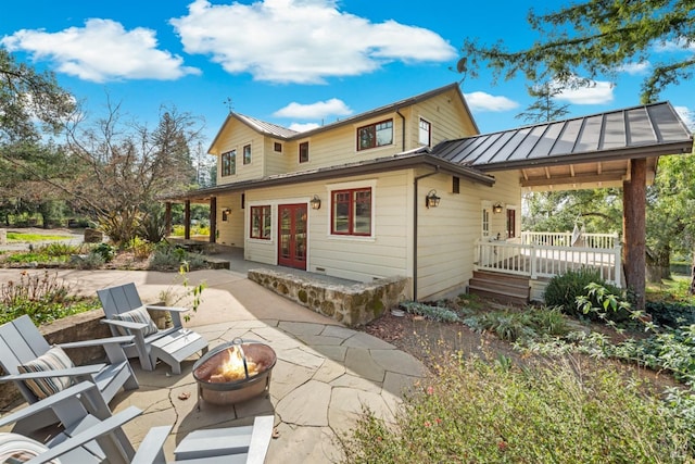 back of house with french doors, an outdoor fire pit, a standing seam roof, a patio area, and metal roof