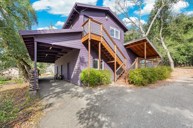 view of front of house with stairs, aphalt driveway, and a carport