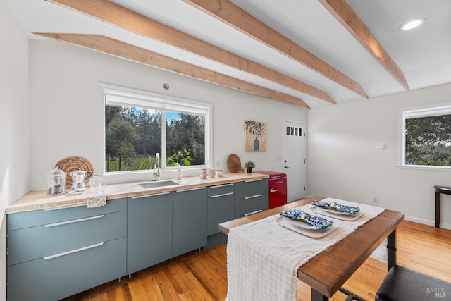 kitchen featuring recessed lighting, a sink, light countertops, beam ceiling, and light wood finished floors