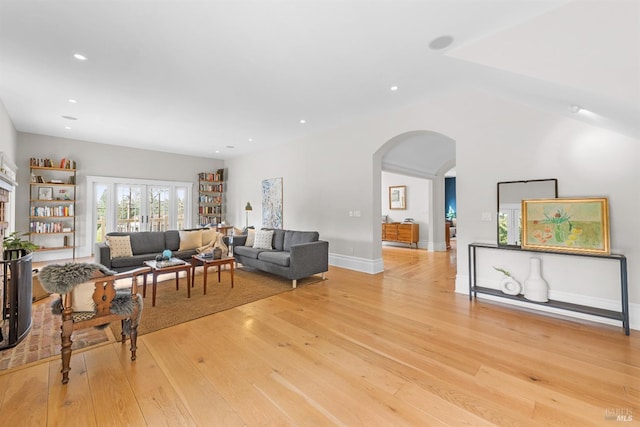 living area with arched walkways, french doors, recessed lighting, light wood-style flooring, and baseboards