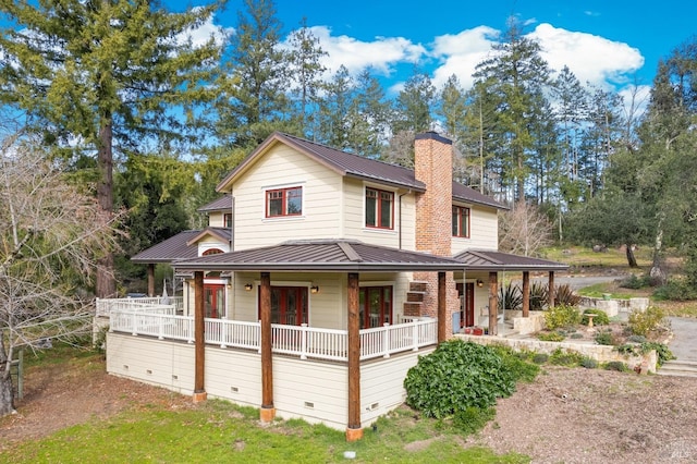 country-style home with a standing seam roof, metal roof, covered porch, crawl space, and a chimney