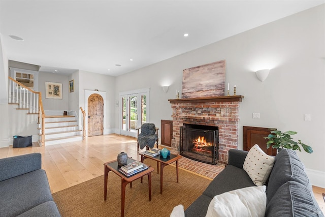 living area with baseboards, hardwood / wood-style flooring, stairway, a brick fireplace, and recessed lighting