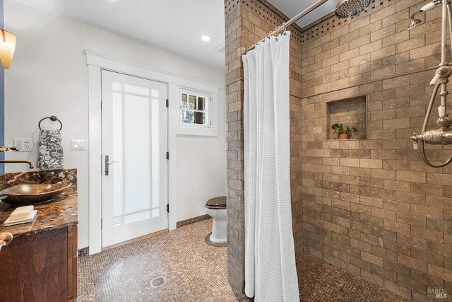 bathroom with toilet, tiled shower, and vanity