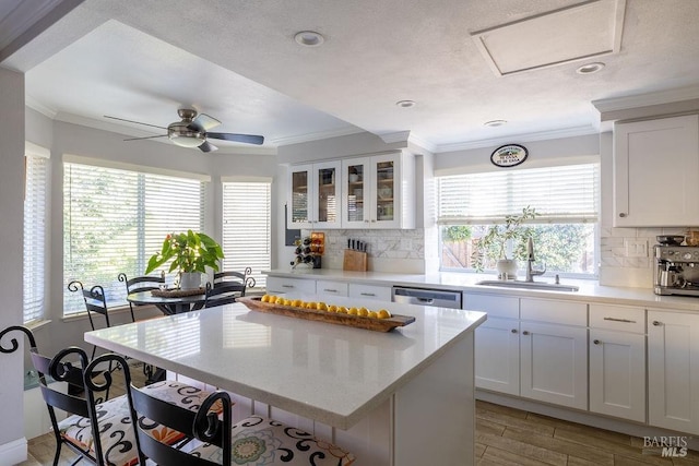 kitchen featuring a sink, white cabinetry, light countertops, ornamental molding, and dishwasher